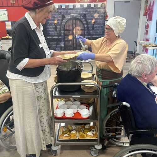 Zwei ältere Frauen in historischer Kleidung servieren Suppe auf einem Fest im Speisesaal