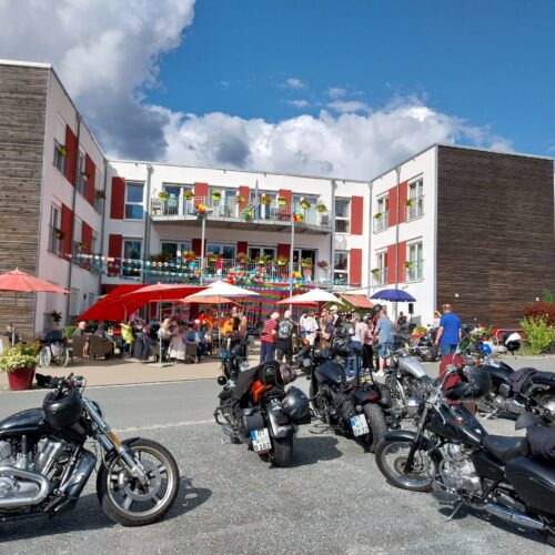 Zahlreiche Menschen feiern fröhlich vor einem modernen Gebäude mit bunten Dekorationen