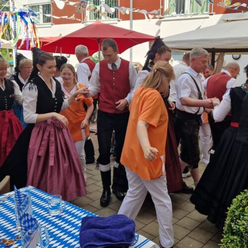 Gruppe von fröhlichen Menschen in traditionellen Trachten tanzt auf einem Fest im Freien